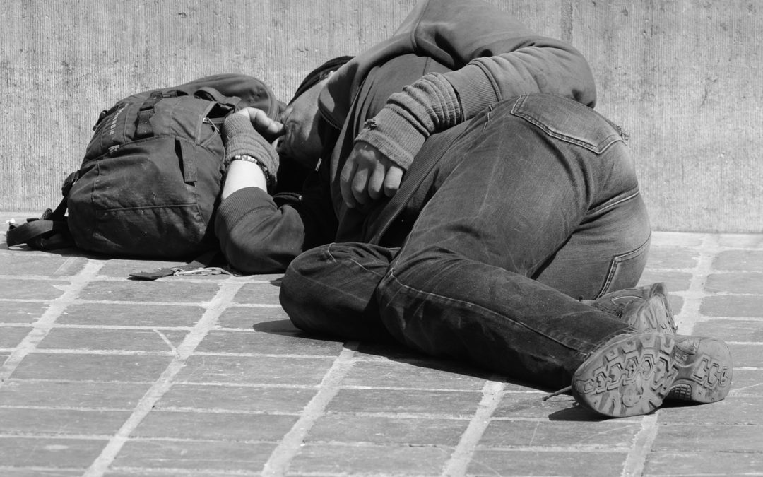 homeless man sleeping on sidewalk