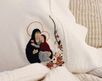 pillow on a bed; an icon of St. Anna with the Theotokos is embroidered on the corner