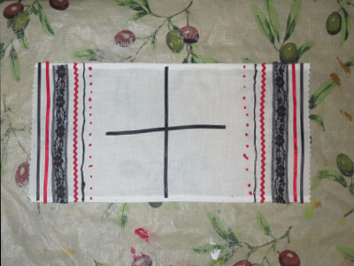 a completed basket cover with ribbons, lace, and a cross in the middle of the cover